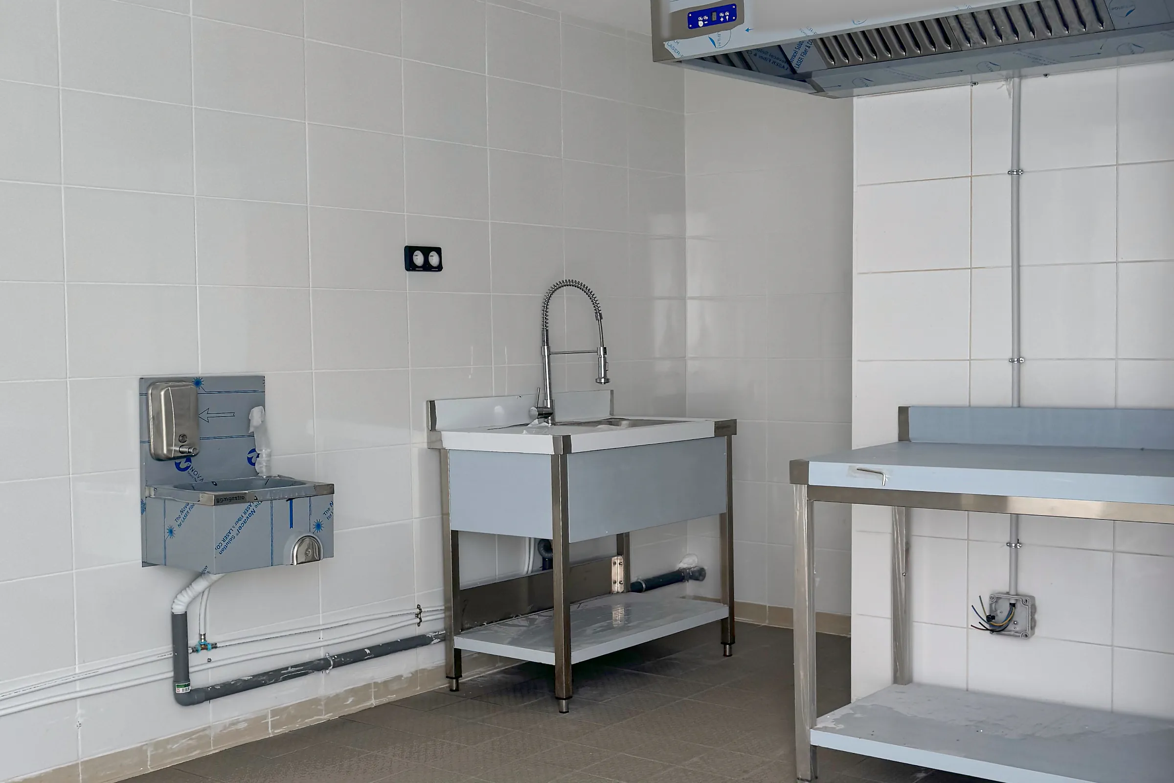 Vue d'ensemble d'un laboratoire Hub Kitchen Porte de Gentilly : hotte, gaine d'extraction, lave-mains, plonge et table inox