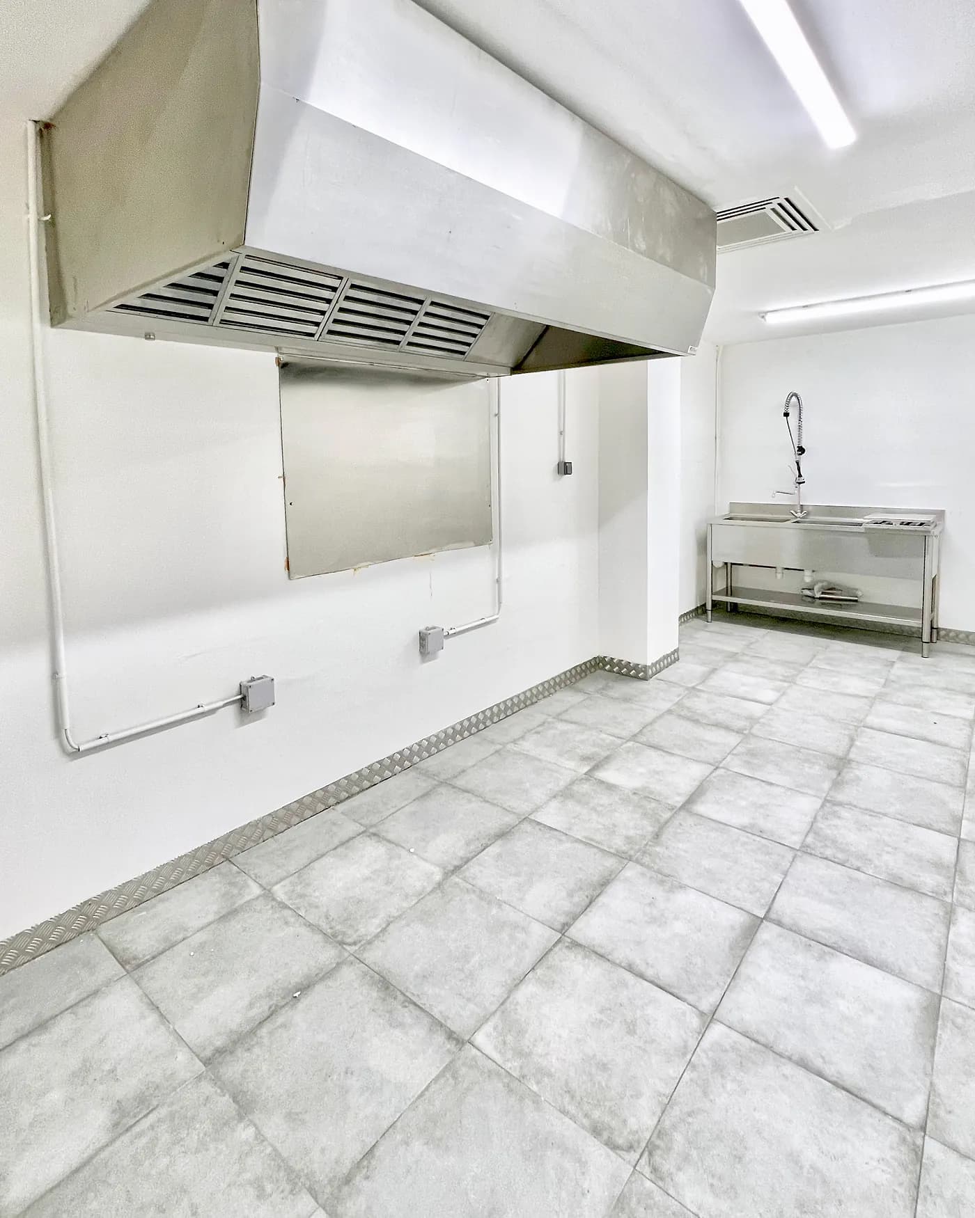 Laboratoire Hub Kitchen : hotte inox à filtres, crédence inox et plonge inox avec douchette (photo d'un autre site du réseau)